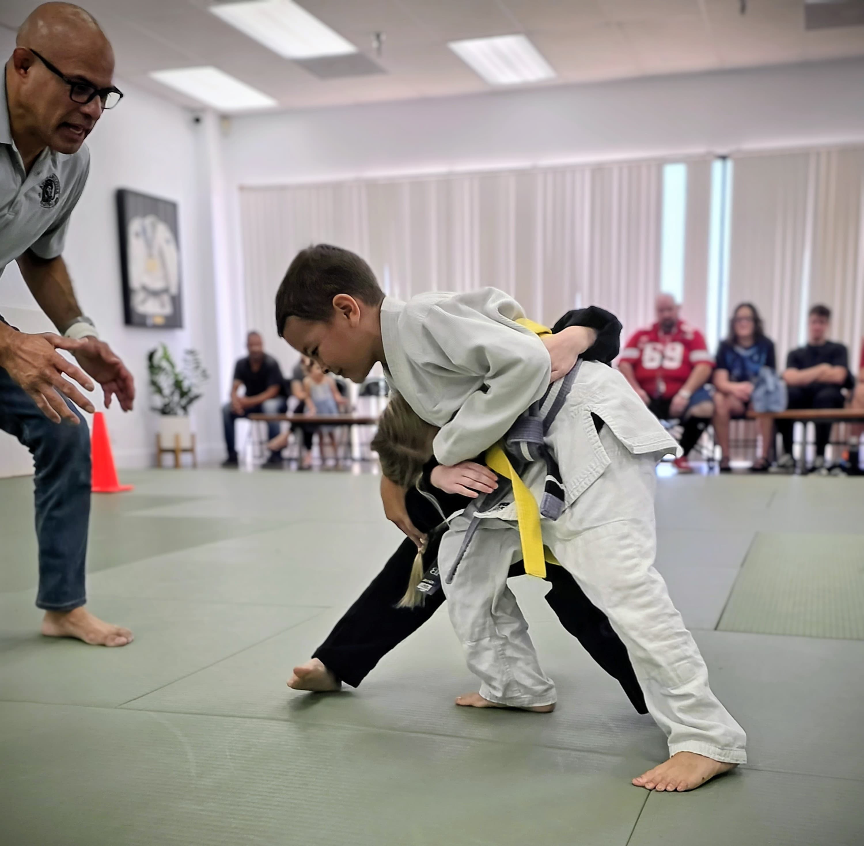 Coach teaching takedown to youth student